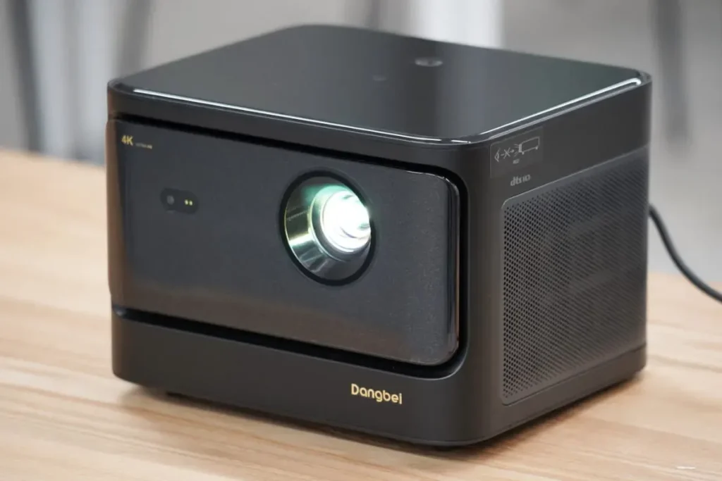 Black Dangbei Mars Pro 4K projector on a wooden table with a glowing lens.