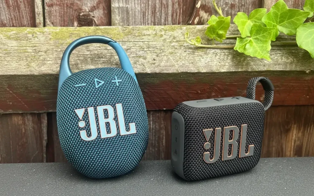 Teal JBL Clip 5 and black JBL Go 4 speakers side by side outdoors.