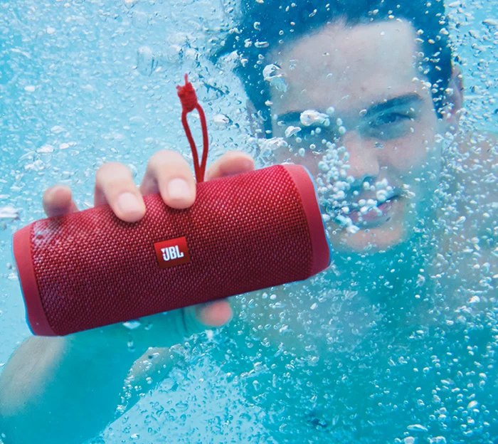 Red JBL Flip 4 speaker submerged underwater showing IP67 JBL Speakers waterproof rating.