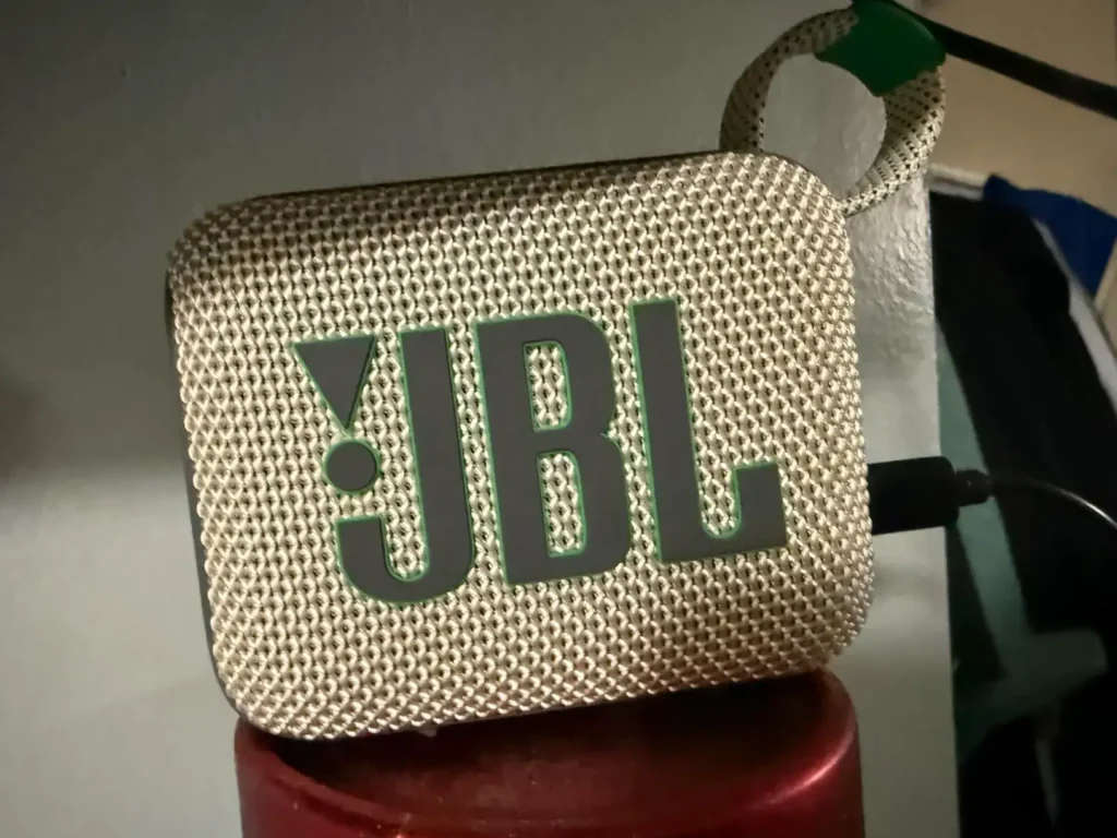JBL Go 4 waterproof Bluetooth speaker in white and teal being charged.