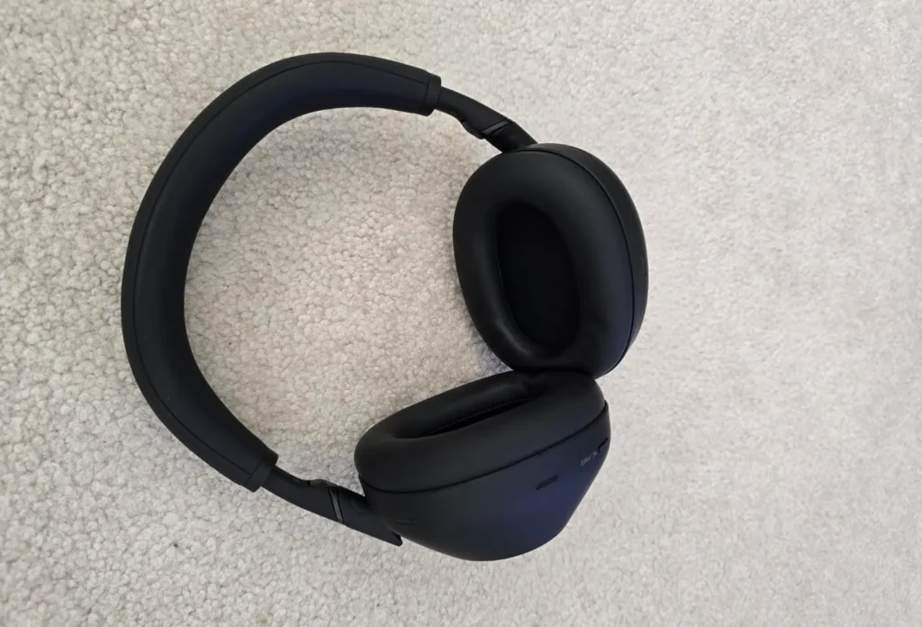 Overhead view of black Sony WH-1000XM4 headphones on a white textured carpet.